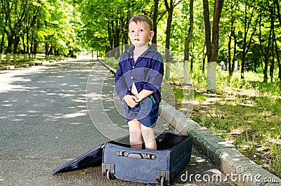 Cute young boy standing in an open suitcase