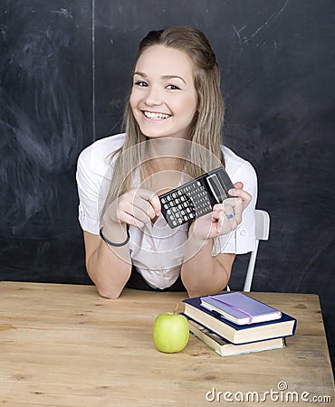 Cute young student near blackboard with copy book calculator pen, copy space