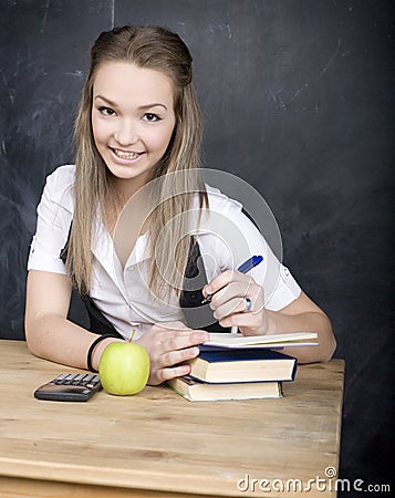 Cute young student near blackboard with copy book calculator pen, copy space