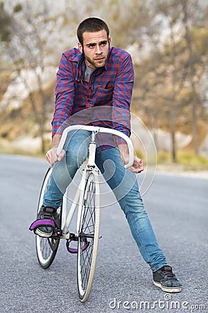 Cyclist man riding fixed gear sport bike in sunny day