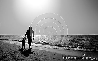 Dad and child on the beach at at sunset