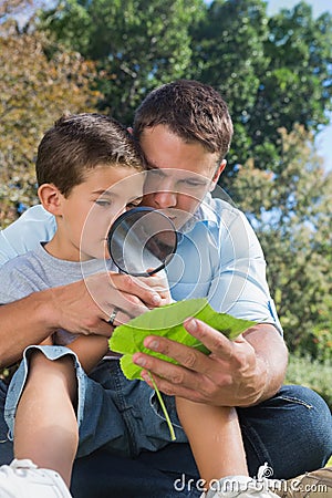 Dad and son inspecting leaf with a magnifying glass