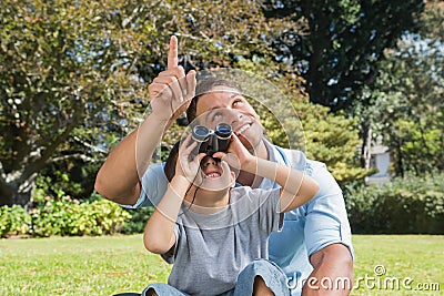 Dad and son looking at the sky with binoculars