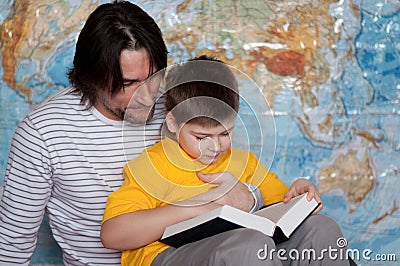 Dad and son reading book on a map of the world