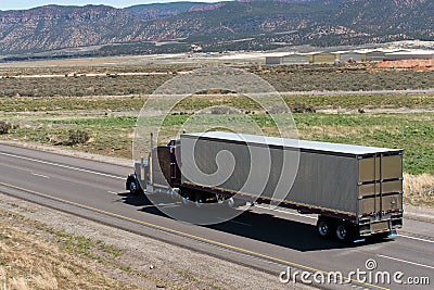 Dark Classic semi truck and trailer on the road with nature view