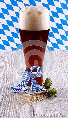 Dark wheat beer in glass with blue ribbon on white wood background