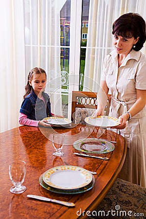 Daughter and mom setting the table