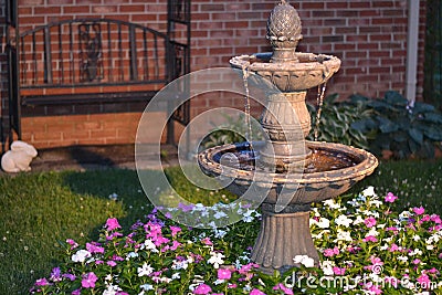 Decorative home water fountain in a bed of flowers