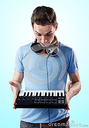 Deejay with headphones holding midi keyboard in hands