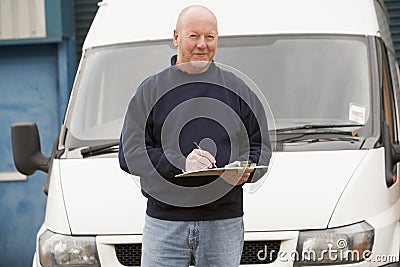 Deliveryperson standing with van and writing