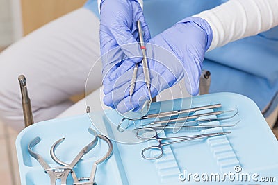 Dentist in blue scrubs holding dental tools