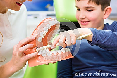 Dentist explaining boy cleaning tooth