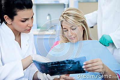 Dentist showing female patient dental X-rays