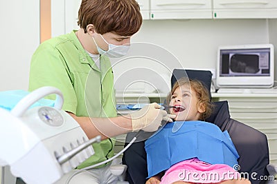 Dentist treats teeth of girl lying in chair