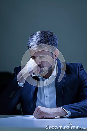 Depressed elegant man sitting at the table