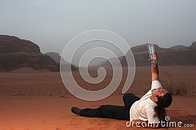 Desperate man in the desert drinking last drops of water from an empty bottle