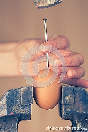 Detail of a Hand Trying to Break an Egg with a Nail