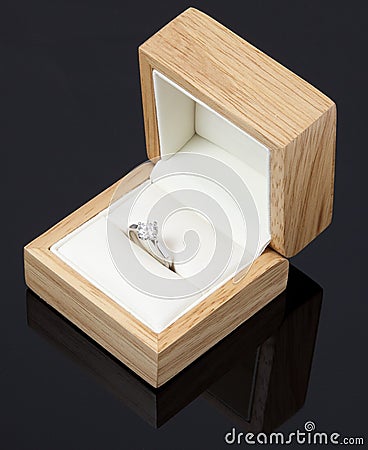  gold and diamond engagement ring in a wooden box on black background