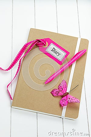 Diary with pink decorations on wooden surface