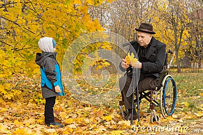 Disabled grandfather and child in an autumn park