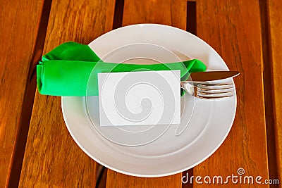 Dishware and blank paper card on table in restaurant