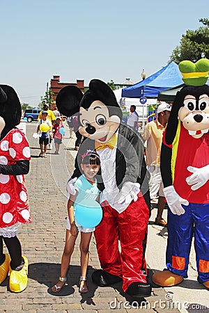 Disney Mickey Mouse, Goofy and Minnie Mouse with small girl at festival