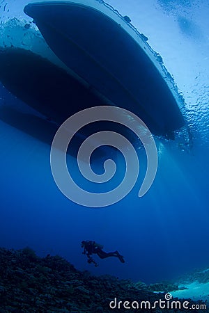 Scuba Diver below boat underwater scene