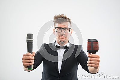 DJ in tuxedo posing with two microphones
