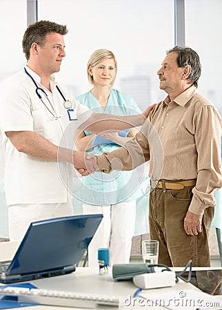 Doctor congratulating senior patient on recovery