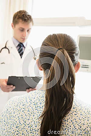 Doctor discussing medical chart with a patient sitting on a hospital bed