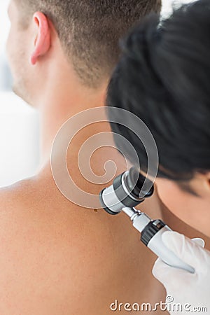 Doctor examining melanoma on back of man