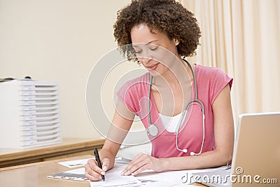 Doctor with laptop writing in doctor s office