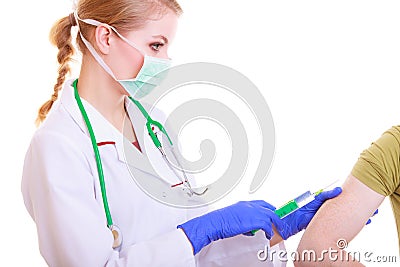 Doctor or nurse in facial mask with syringe giving injection to patient