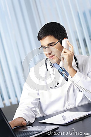 Doctor with phone and laptop, at office