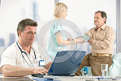 Doctor sitting at desk, nurse examining patient.