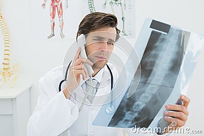 Doctor with spine xray picture using the telephone