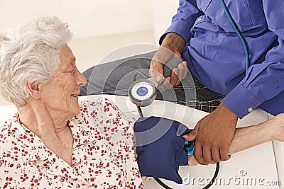 Doctor taking blood pressure to an elderly patient at home