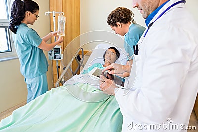 Doctor Using Digital Tablet With Nurses Examining