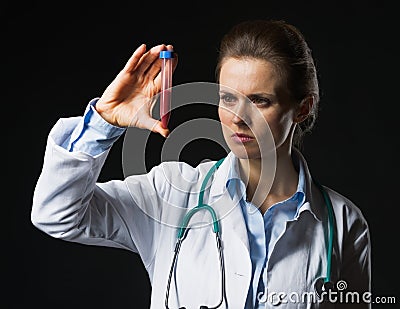 Doctor woman looking on test tube on black background