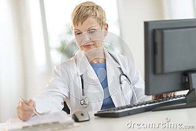 Doctor Working At Computer Desk In Clinic