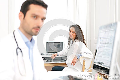 Doctor working at the office with nurse in background