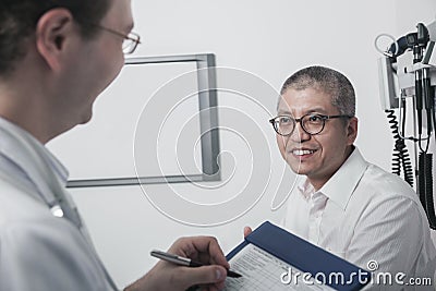 Doctor writing on medical chart with a smiling patient