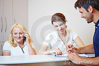 Doctors assistant helping patient to fill out form