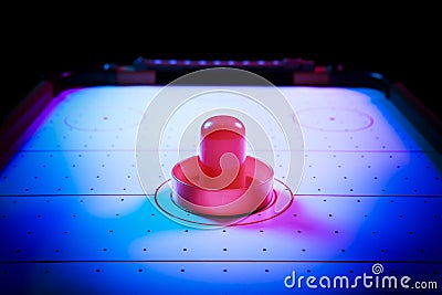 Dramatic lit air hockey table with puck and paddles