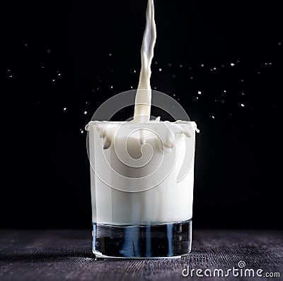 Milk pouring into a glass on black board