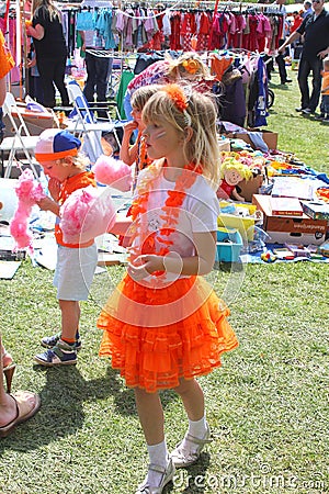 Dutch girl in orange princess dress enjoys cotton candy, Holland