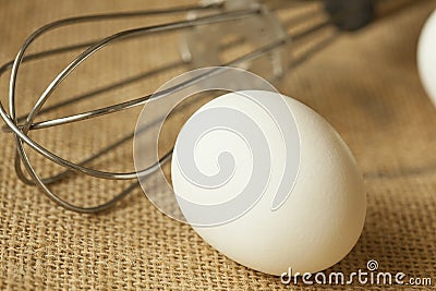 An Egg and whisk isolated on table mat