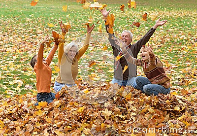 Elderly couple and children throwing leaves