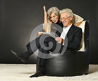 Elderly couple reading newspaper