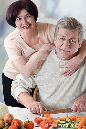 Elderly happy couple cooking at kitchen